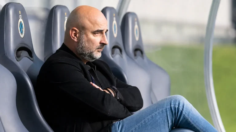 Een clubofficial van Anderlecht zit geconcentreerd op de bank langs het veld.
