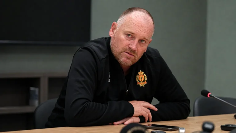 Fred Vanderbiest spreekt tijdens een persmoment aan een tafel in clubkleding.