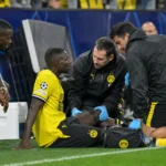 Medische staf helpt een geblesseerde speler in geel-zwart aan de zijlijn.