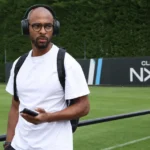 Denis Odoi in witte vrijetijdskleding bij een Club NXT-trainingscomplex.