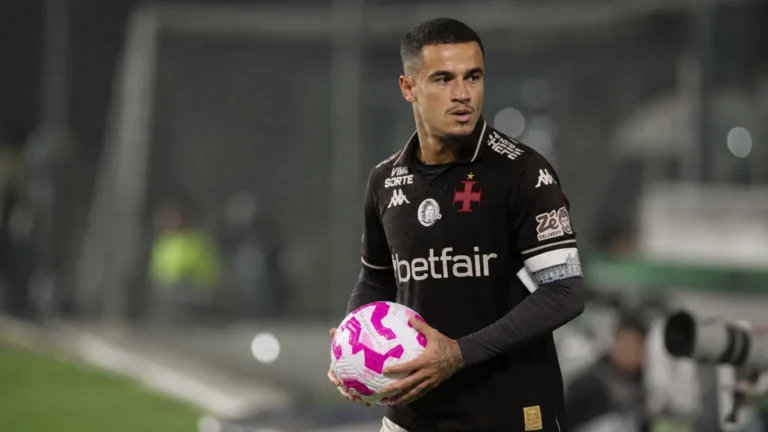 Philippe Coutinho houdt een bal vast in een zwart voetbaltenue op het veld.
