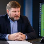 Hein Vanhaezebrouck in een voetbalstudio met een subtiel Club Brugge-wanddetail op de achtergrond.