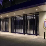 Verlichte ingang van Lotto Park met één Anderlecht-embleem aan de gevel.