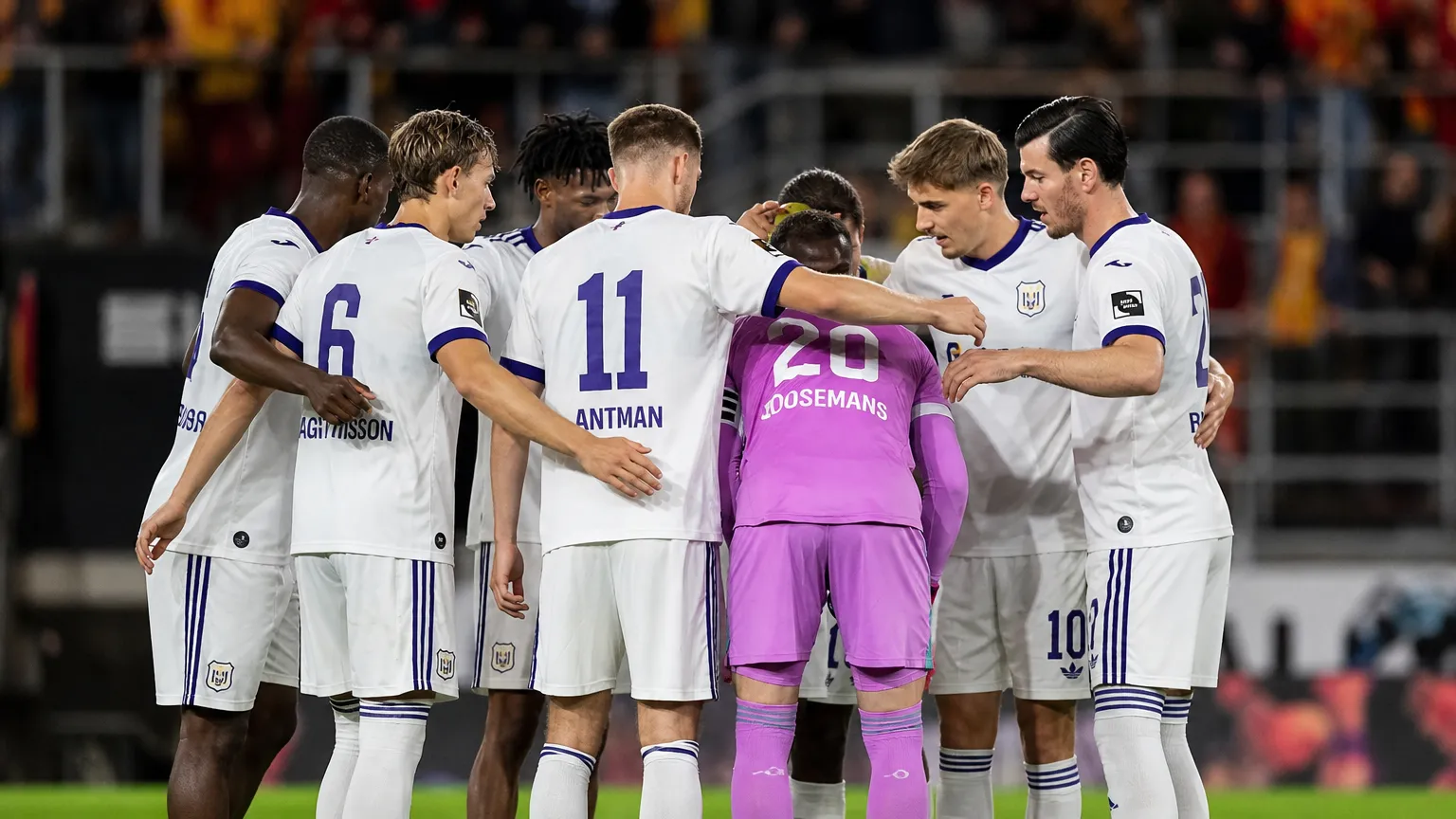 Een groep Anderlecht-spelers in witte wedstrijdshirts verzamelt zich na afloop op het veld.