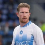 Een voetballer in een wit-blauw Napoli-tenue langs de zijlijn van een stadion.
