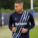 Richarlison warmt op in een donker Tottenham-tenue aan de rand van het trainingsveld.