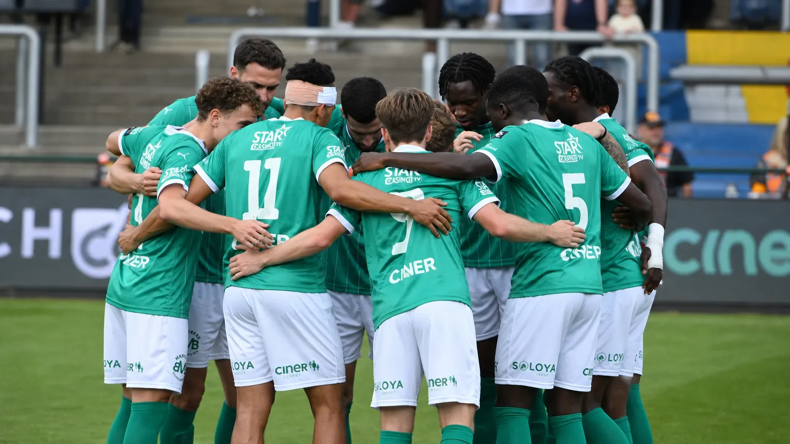 Een groep spelers van Lommel SK vormt een huddle naast het veld.