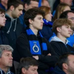 Een groep Club Brugge-supporters met blauw-zwarte sjaals op de tribune.