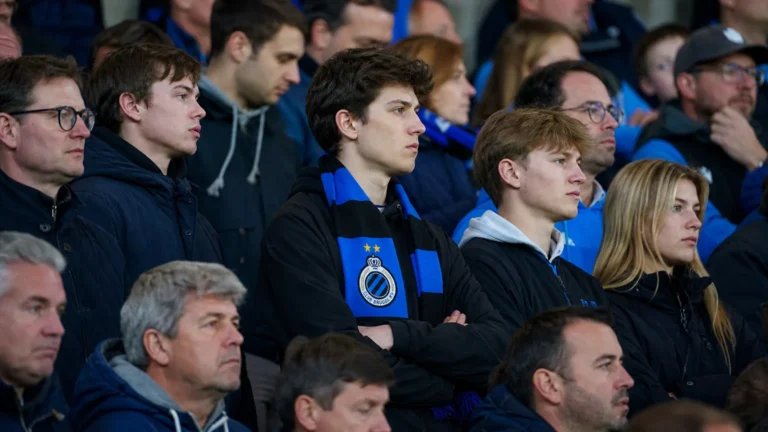 Een groep Club Brugge-supporters met blauw-zwarte sjaals op de tribune.