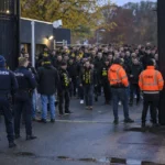 Politie en veiligheidsmedewerkers bij een groep Lierse-supporters aan de rand van het veld.