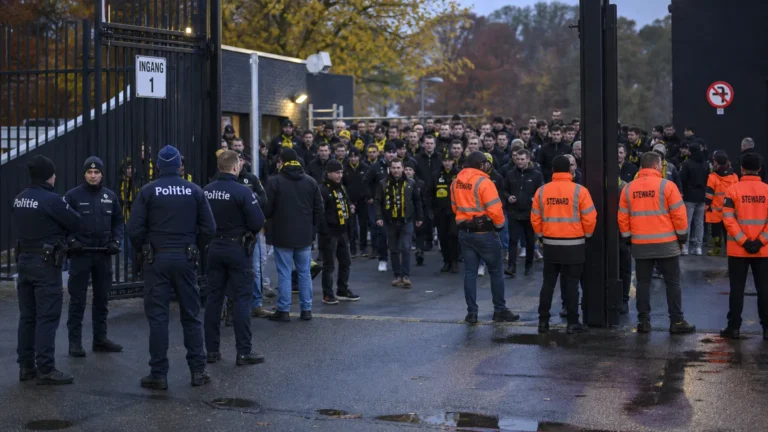 Politie en veiligheidsmedewerkers bij een groep Lierse-supporters aan de rand van het veld.
