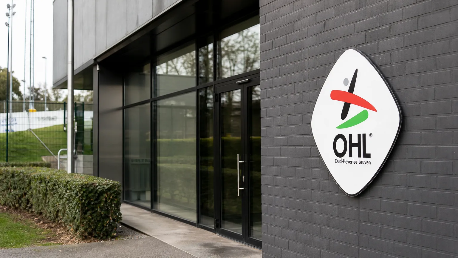 Lege ingang van een OH Leuven-clubgebouw met een vast clubembleem aan de gevel.
