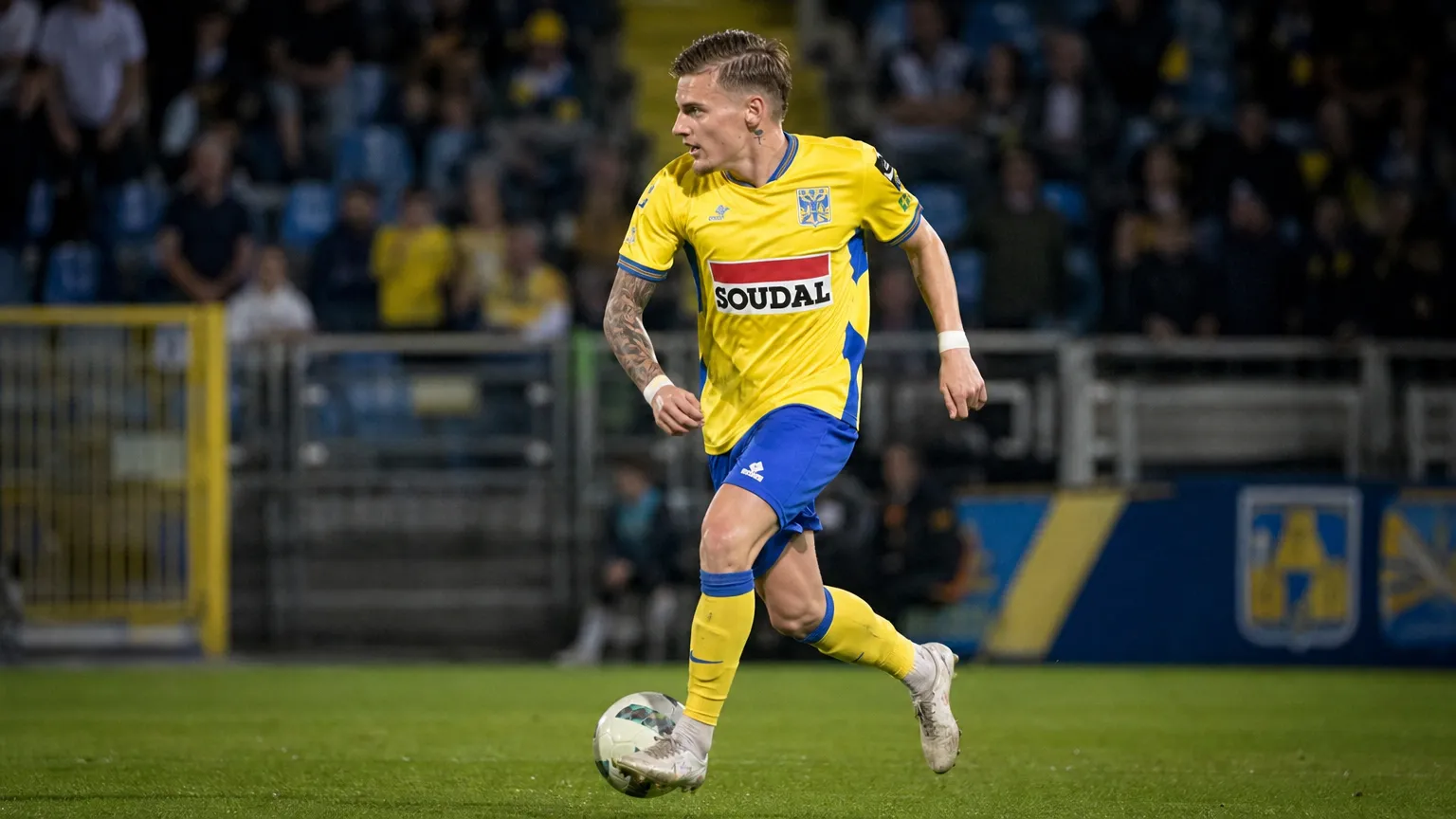 Een Westerlo-speler in geel-blauw tenue in actie tijdens een wedstrijd.