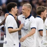 Een groep Club Brugge-spelers in witte wedstrijdshirts viert samen tijdens een wedstrijd.