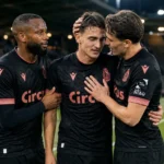 Dennis Eckert Ayensa staat na de match met twee ploegmaats van Standard op het veld.