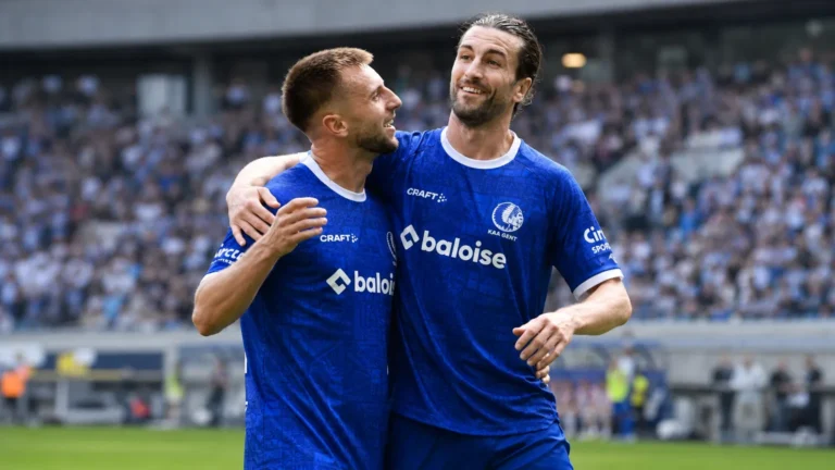 Twee KAA Gent-spelers vieren samen een moment op het veld.