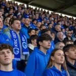 Collectieve KRC Genk-supporters met blauw-witte sjaals in de Cegeka Arena voor de aftrap.