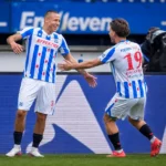 Twee spelers van sc Heerenveen vieren samen een moment langs het veld.