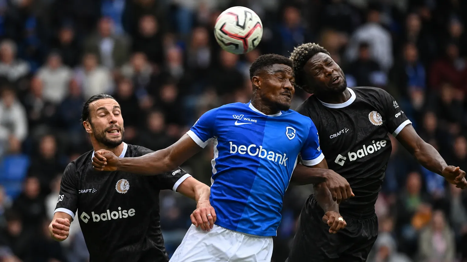 Spelers van KRC Genk en KAA Gent in een luchtduel tijdens de wedstrijd.