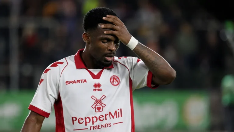 Een speler in een wit-rood tenue reageert tijdens een voetbalwedstrijd.