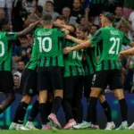 Spelers van Sassuolo in groen-zwarte shirts vieren samen op het veld.