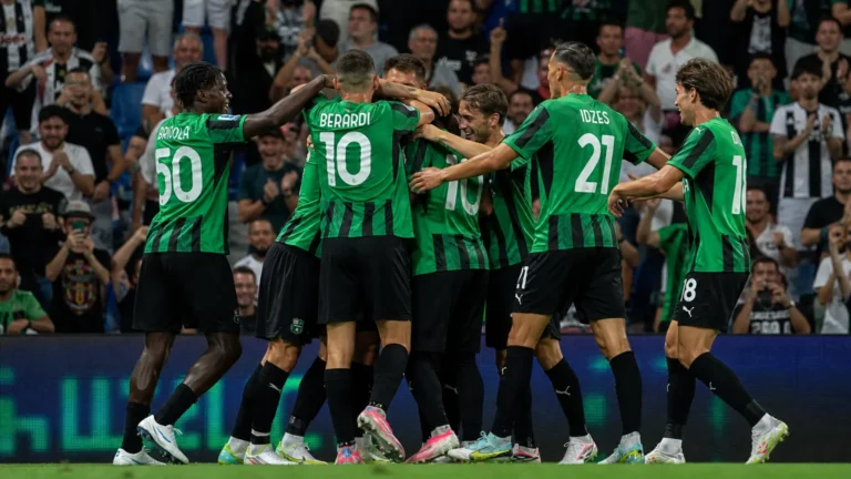 Spelers van Sassuolo in groen-zwarte shirts vieren samen op het veld.