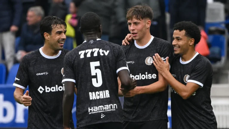 Een groep KAA Gent-spelers in zwarte wedstrijdshirts verzamelt zich na de wedstrijd aan de rand van het veld.