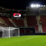 Leeg doelgebied in het AZ-stadion met een verlicht AZ-clubbord op de tribune.