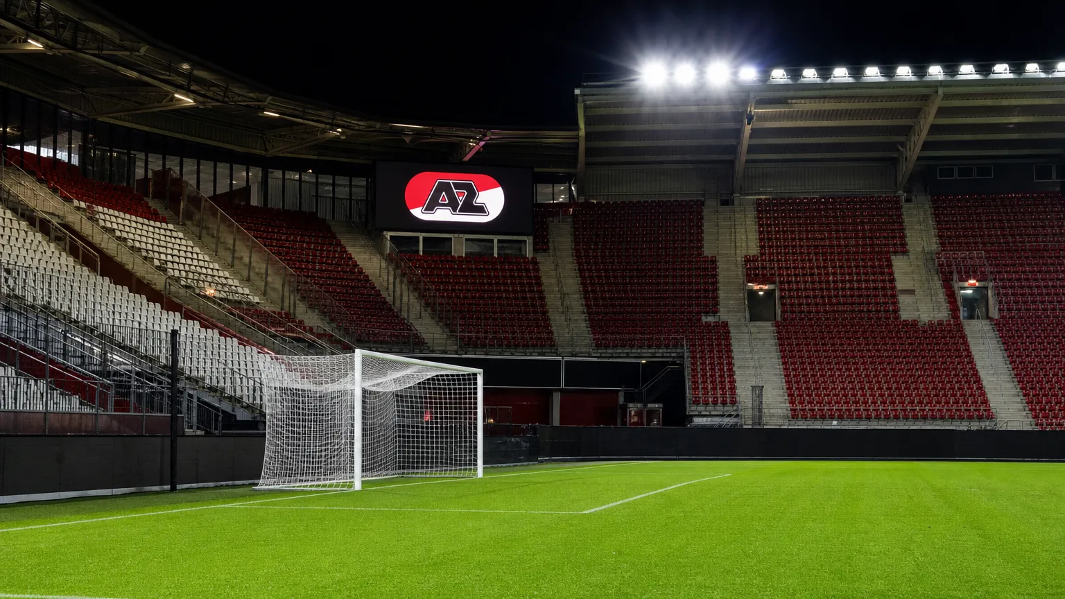 Leeg doelgebied in het AZ-stadion met een verlicht AZ-clubbord op de tribune.