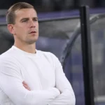Michiel Jonckheere staat in een witte trui langs de zijlijn van een voetbalstadion.