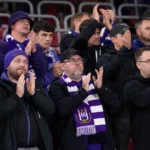 Een compacte groep Anderlecht-supporters in het uitvak met paars-witte sjaals.