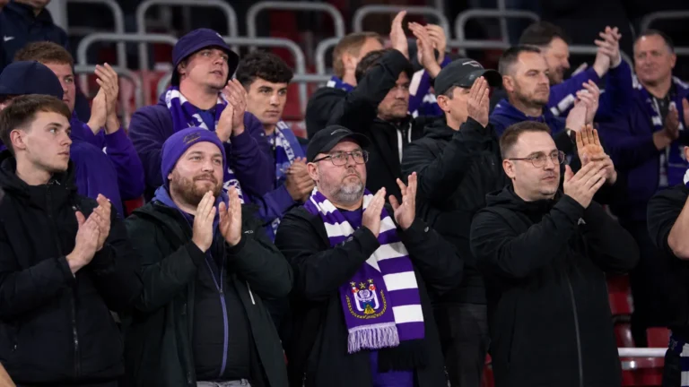 Een compacte groep Anderlecht-supporters in het uitvak met paars-witte sjaals.