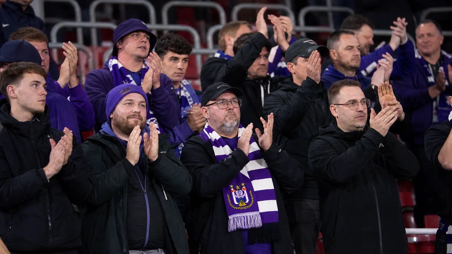 Een compacte groep Anderlecht-supporters in het uitvak met paars-witte sjaals.