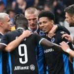Een groep spelers van Club Brugge viert samen op het veld in zwart-blauwe wedstrijdtenues.