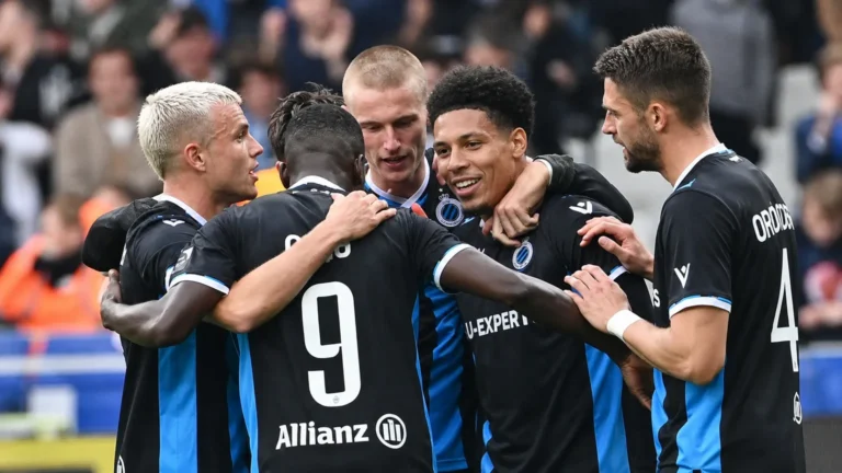 Een groep spelers van Club Brugge viert samen op het veld in zwart-blauwe wedstrijdtenues.