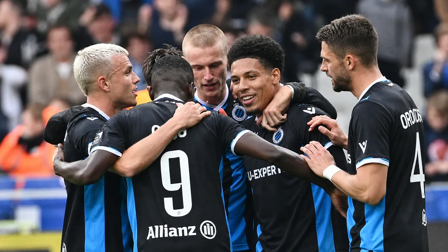 Een groep spelers van Club Brugge viert samen op het veld in zwart-blauwe wedstrijdtenues.