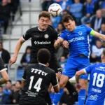 Een groep spelers strijdt om een hoge bal tijdens een wedstrijd.