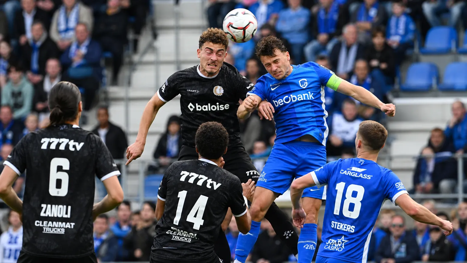 Een groep spelers strijdt om een hoge bal tijdens een wedstrijd.