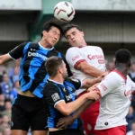 Spelers van Club Brugge en Antwerp strijden in de lucht om de bal.