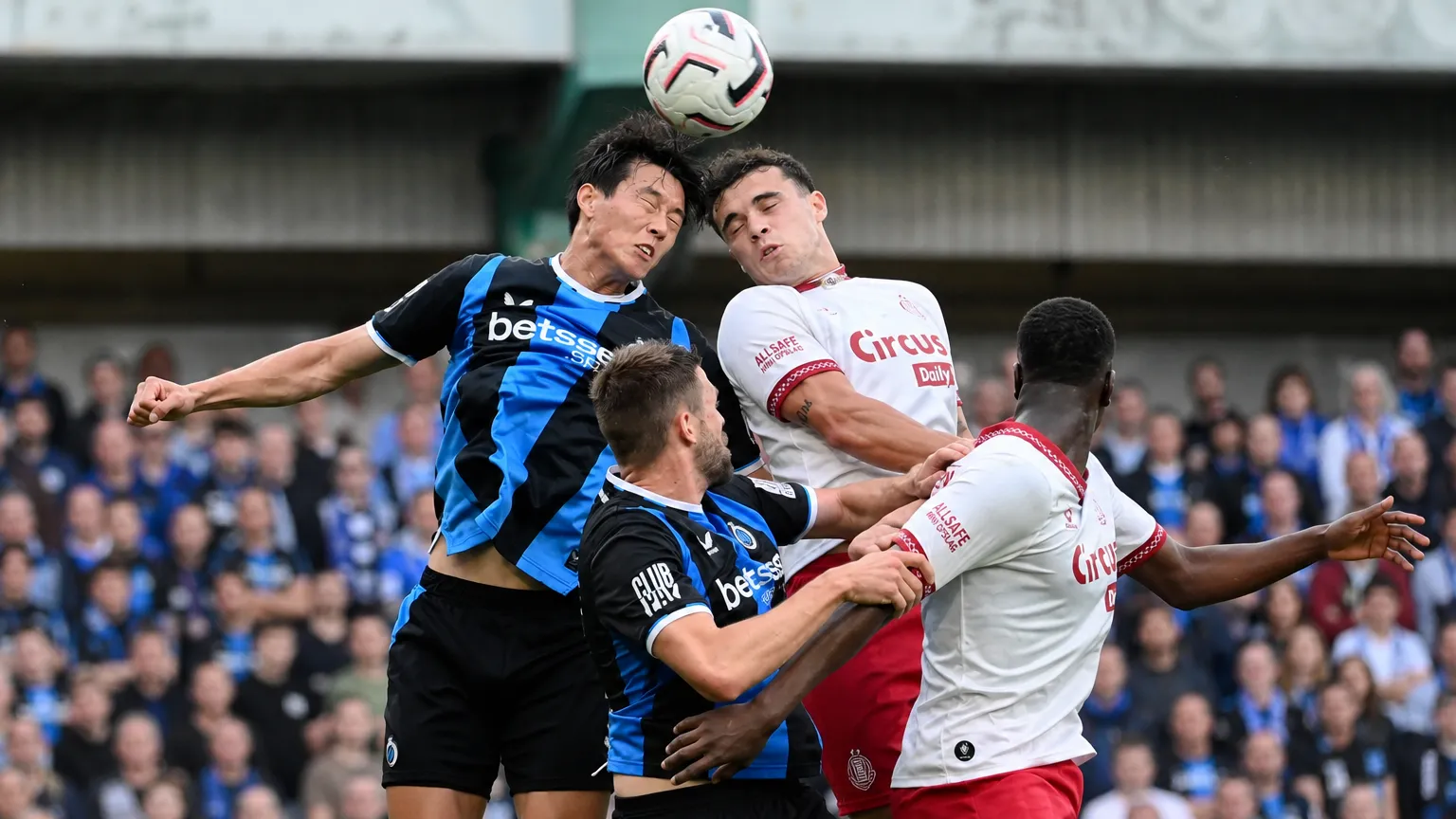 Spelers van Club Brugge en Antwerp strijden in de lucht om de bal.