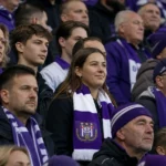 Een groep Anderlecht-supporters op de tribune met een paars-witte clubsjaal.