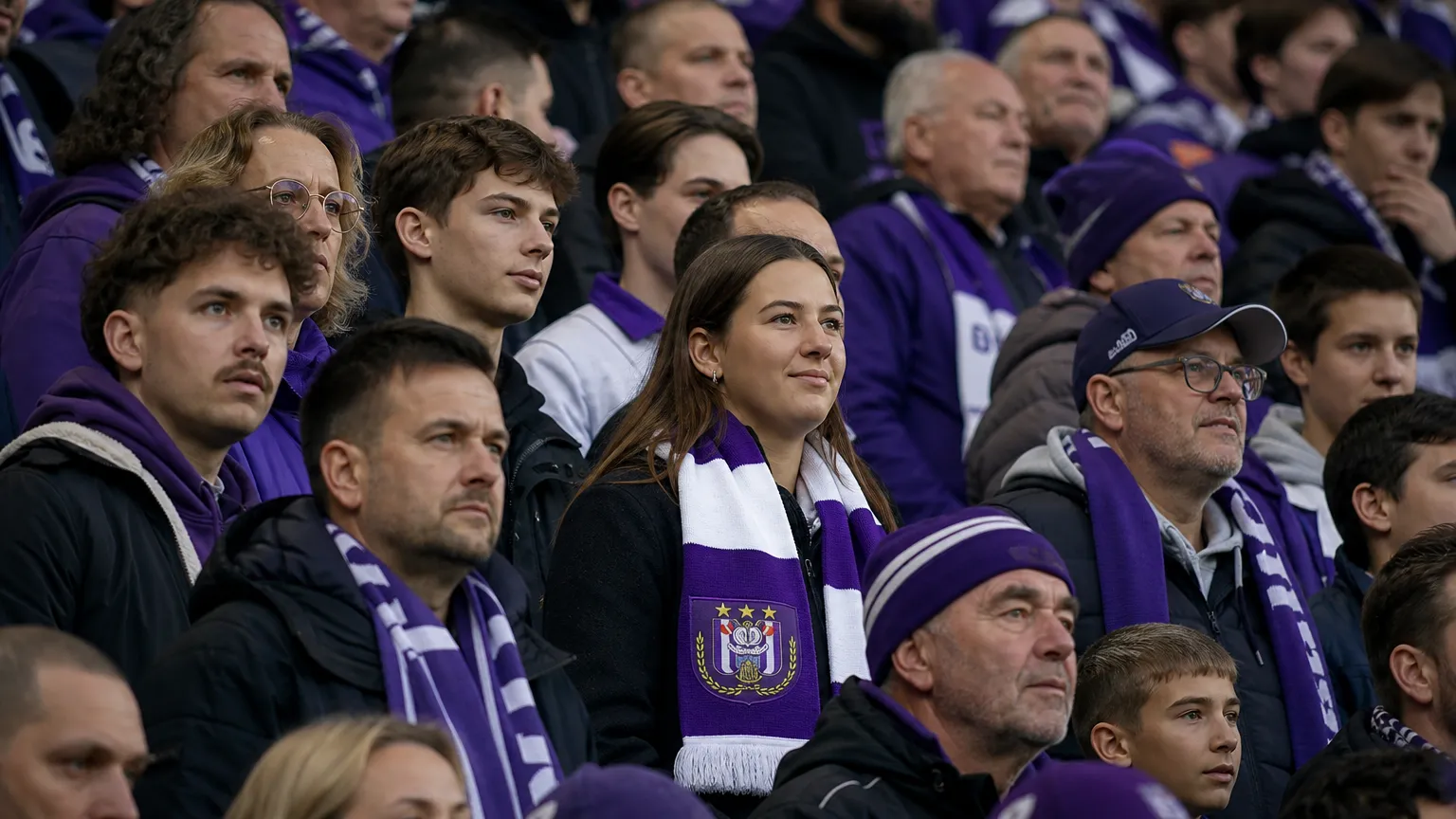 Een groep Anderlecht-supporters op de tribune met een paars-witte clubsjaal.