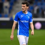 Een KRC Genk-speler in blauw-wit wedstrijdtenue op het veld na de wedstrijd.
