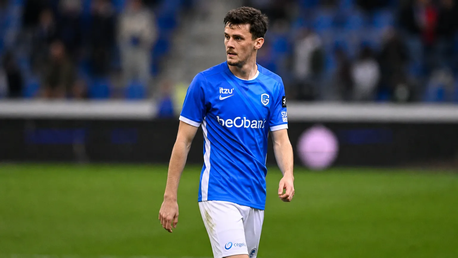Een KRC Genk-speler in blauw-wit wedstrijdtenue op het veld na de wedstrijd.