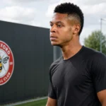 Kaye Furo in een neutrale trainingstop op het trainingscomplex van Brentford, met een clubbord op de achtergrond.