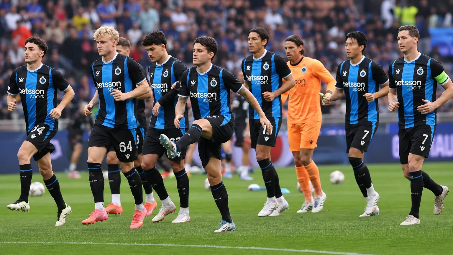 Een groep spelers in zwart-blauwe tenues warmt op het veld op.