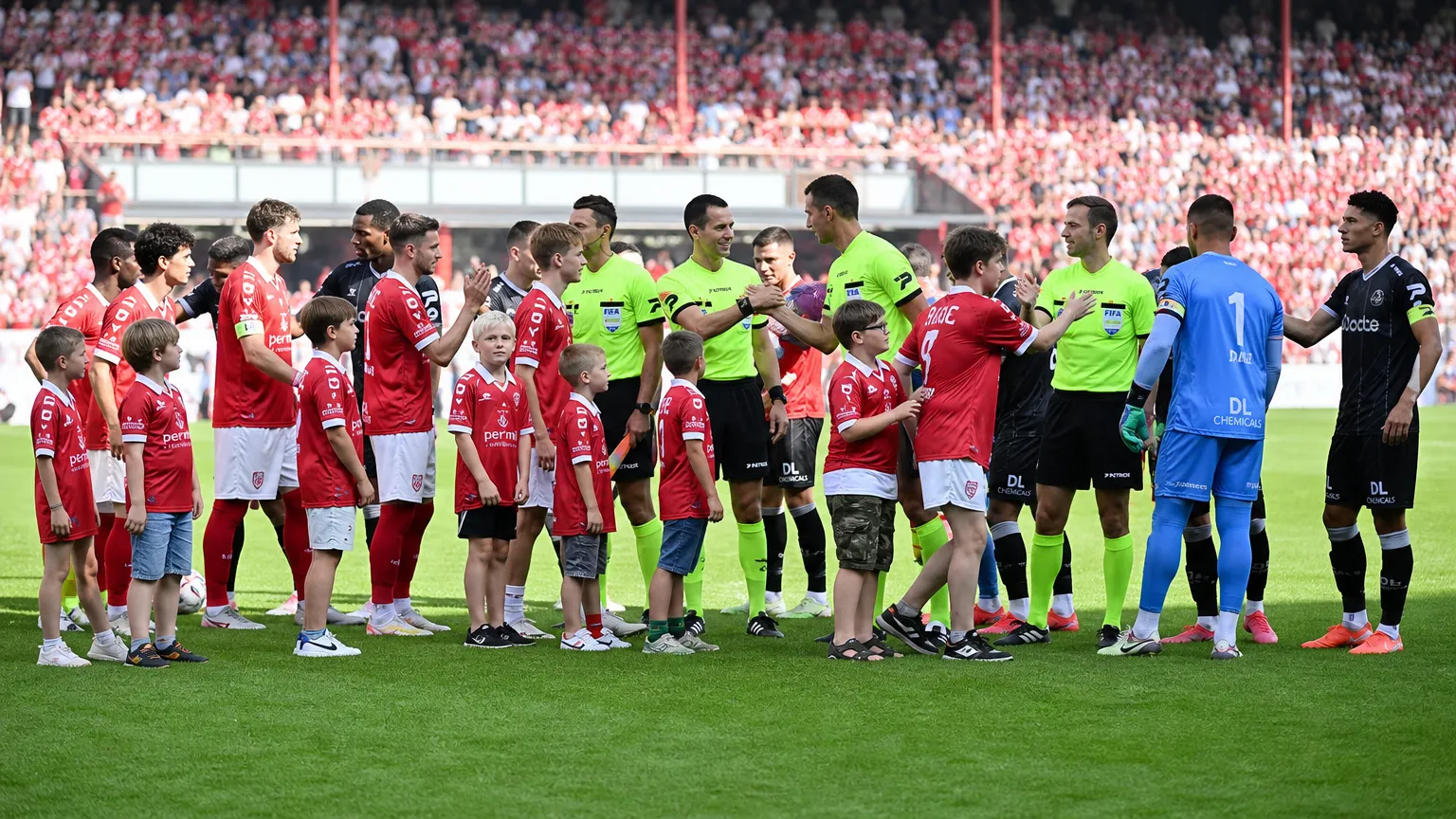 Voetballers en scheidsrechters staan opgesteld op het veld voor een wedstrijd.