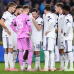 Een groep Anderlecht-spelers overlegt in een kring op het veld, met een doelman in roze tenue.