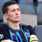 Hans Vanaken in een blauw-zwart Club Brugge-shirt op de tribune van een stadion.