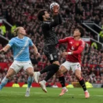 Een doelman en drie spelers in actie voor het doel tijdens een Manchester-derby.